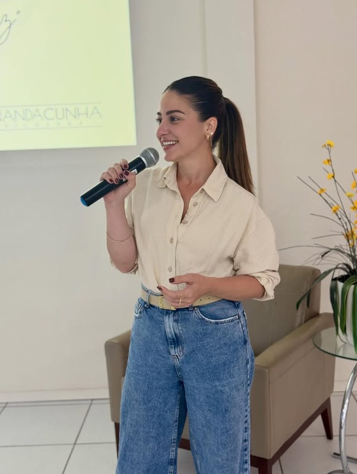 Fernanda Cunha com microfone, durante palestra corporativa